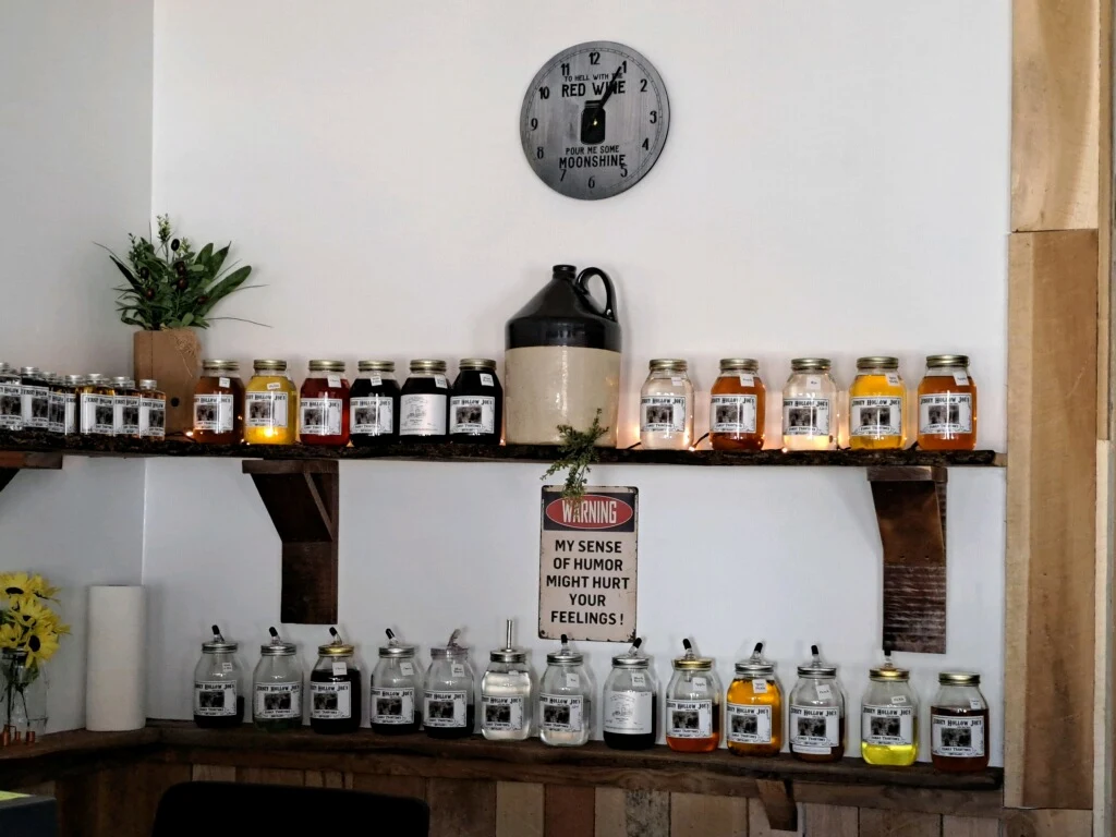 Jars of moonshine lined up on rustic wooden shelves beneath a red wine vs. moonshine clock